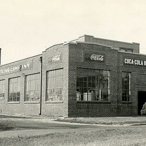 Brick bottling plant building with signs above large windows and truck