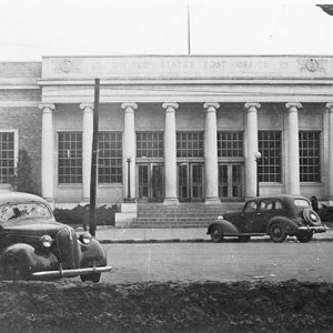 Single-story brick building with eight front columns on parking lot with cars in it
