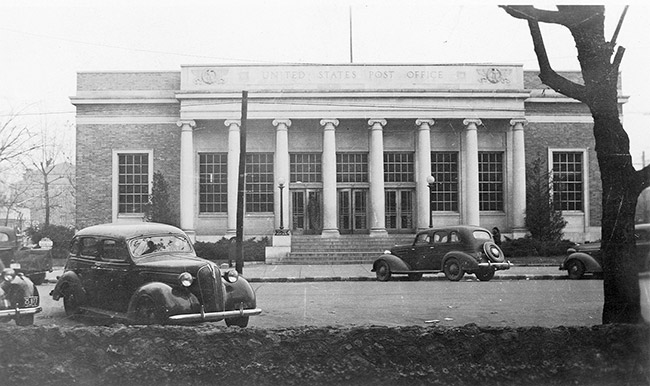 Single-story brick building with eight front columns on parking lot with cars in it