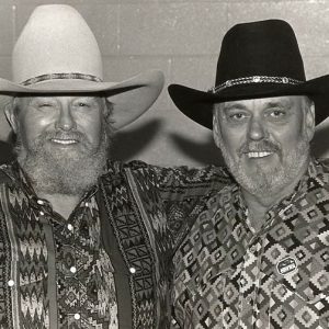 Two white men with beards smiling in colorful shirts and cowboy hats