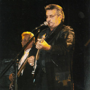 Two white men in black playing electric guitar and bass on stage