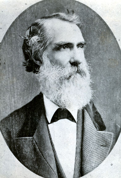 Old white man with long white beard in suit and bow tie