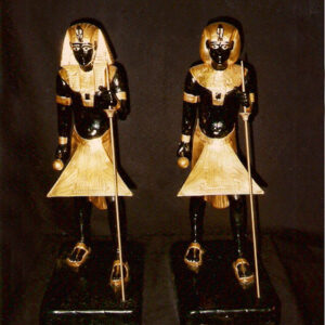 two dark pharaoh figurines with gold accouterments and staffs