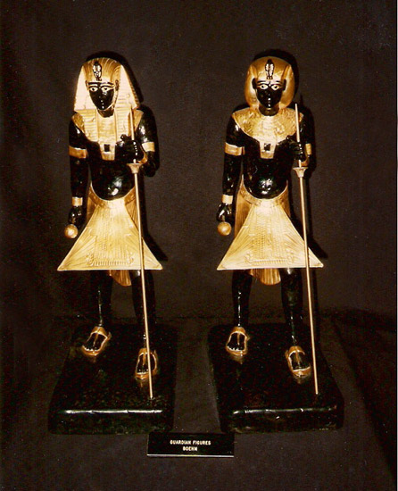 two dark pharaoh figurines with gold accouterments and staffs