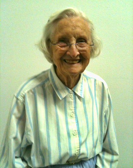 Older white woman with glasses smiling in striped shirt