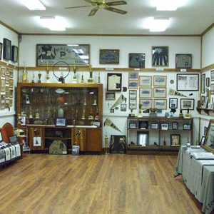 Interior of museum room with walls covered in athletic memorabilia with display cases and wood floors
