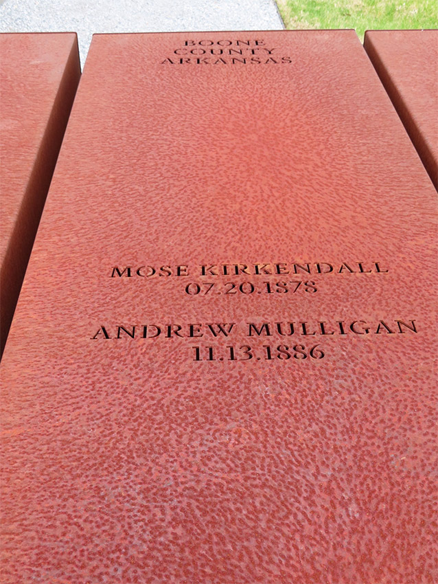 Rust-colored metal rectangle engraved with names and dates