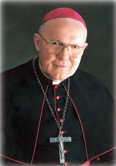 Old white man with glasses wearing a red cap and bishop's robes with crucifix necklace
