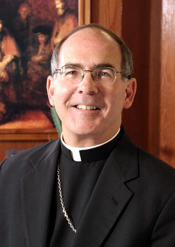 White man wearing glasses in black suit with white clerical collar