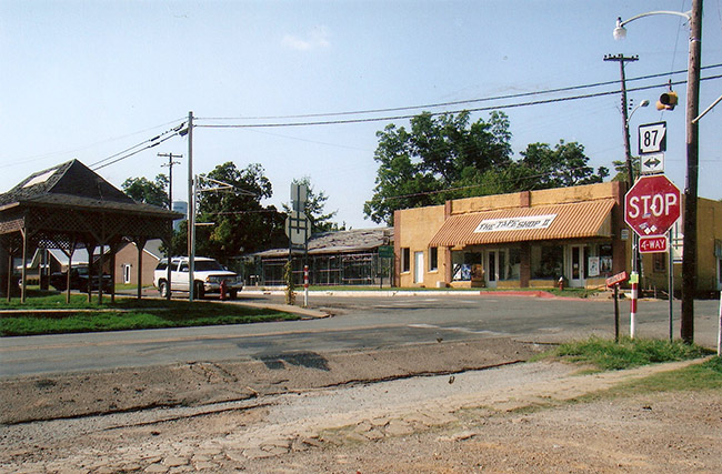four way intersection with stop signs and a gazebo opposite a store
