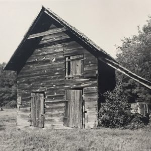 Two-story dilapidated barn with two doors and covered window