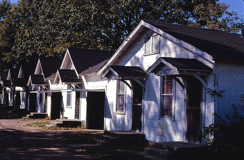 Identical housing units with pairs of front doors and windows and awnings over front steps