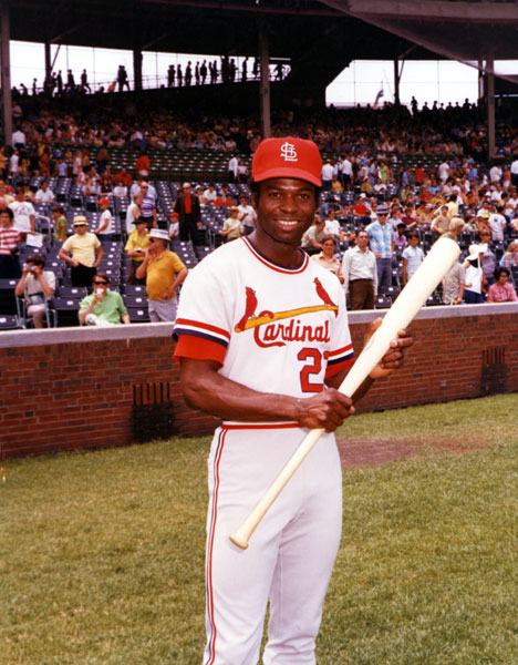 African-American man in a St. Louis Cardinals uniform posing with a bat in a crowded stadium