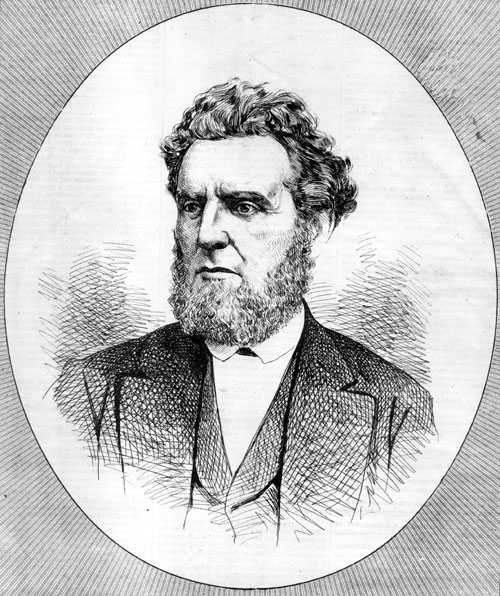 White man with curly hair and beard in suit and vest