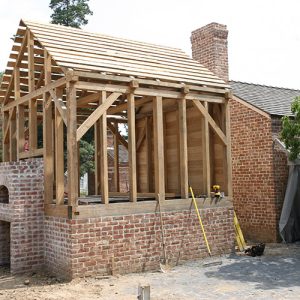 Brick outbuilding with chimney under construction with exposed wooden frame