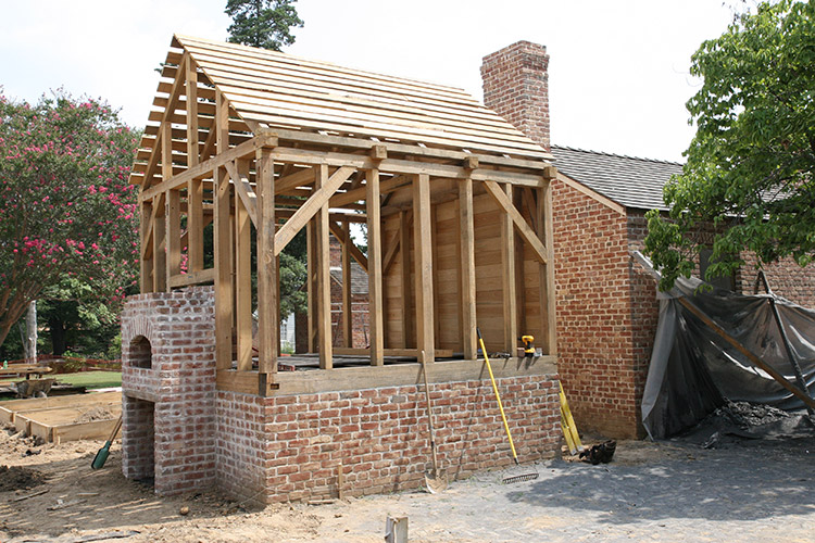 Brick outbuilding with chimney under construction with exposed wooden frame