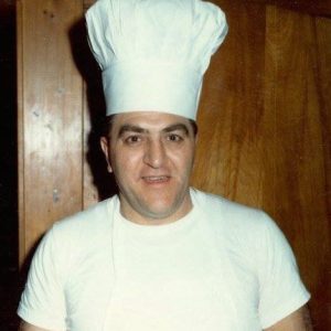 Italian-American man smiling in chef's uniform with hat