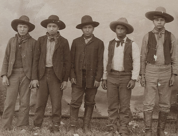 Group of Native American men in suits and hats standing in line