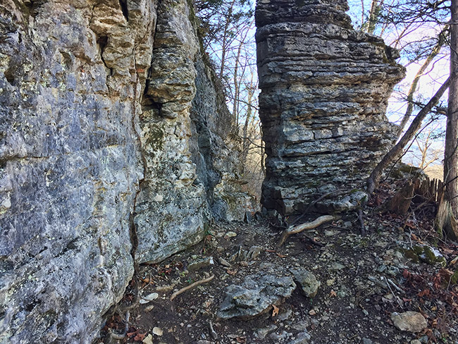 Stone wall and weathered stone pillar in forested area