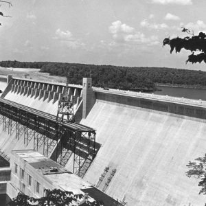 Concrete dam with lake and trees in the background