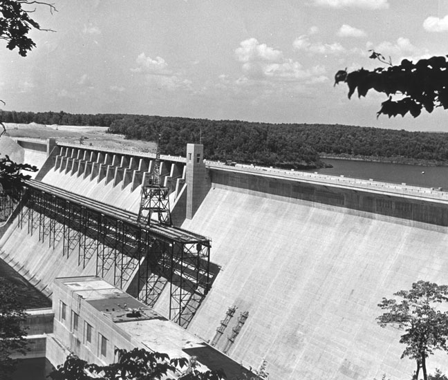 Concrete dam with lake and trees in the background
