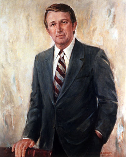 White man with brown hair in blue suit and a striped tie
