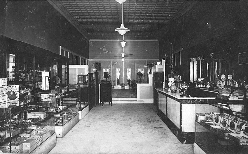Interior of store with hanging light fixtures and glass display cases across from front desk