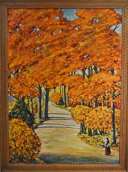 Narrow road between orange and yellow trees with small female figure in foreground