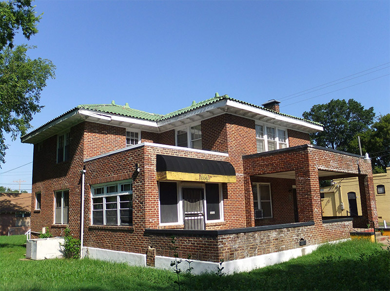 Multistory brick building with covered porch on street