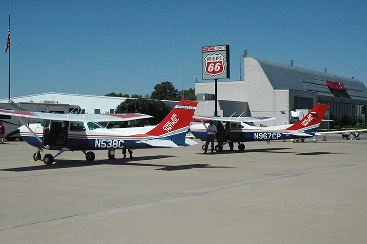 Red-white-and-blue airplanes at airport and "Phillips 66" sign with building in the background
