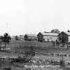Panorama of kitchen, barracks, uniformed men, truck, and rock walls, hand-signed "C.C.C. Camp Nodak - Plainview, Ark. 11-8-33"