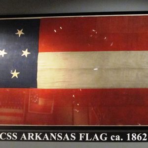 Red white and blue flag with three stripes and seven stars under glass