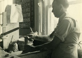 Older white man working at pottery wheel in shop