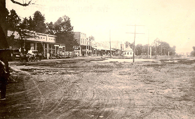 Horse drawn carriage and brick storefronts on dirt roads