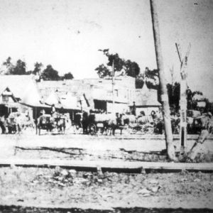 Horse drawn wagons with buildings behind them