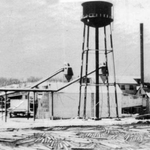 Lumber mill building with four smoke stacks and water tower