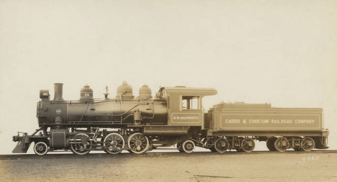 Side view of steam locomotive with coal car on railroad tracks