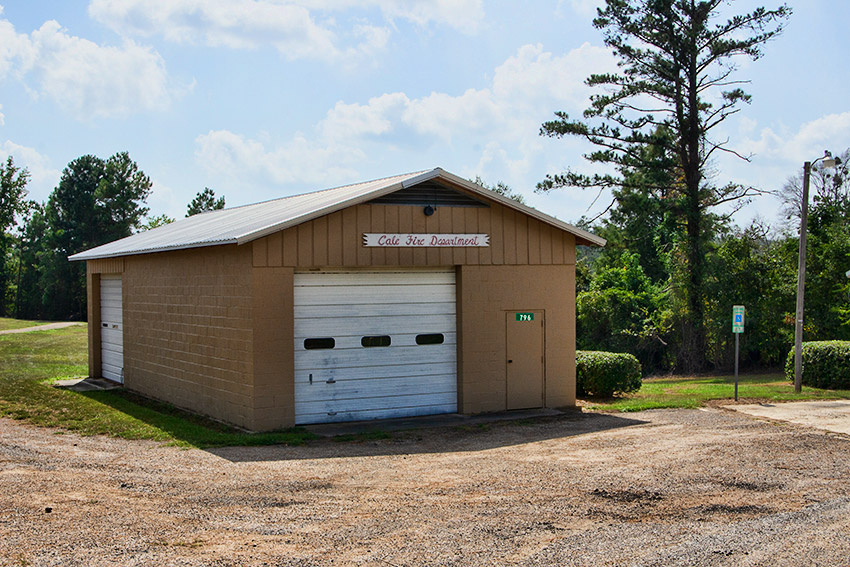 Single-story building with garage door on gravel parking lot