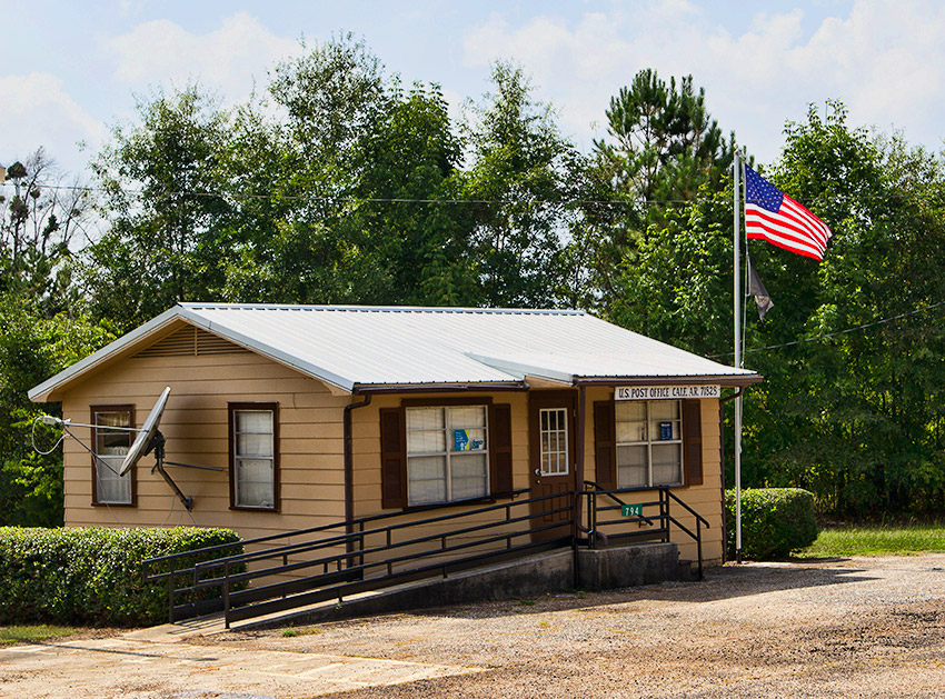 Single-story building with flag pole and wheelchair ramp on gravel parking lot