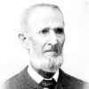 faded black and white photo of older white man with round glasses and beard in suit jacket