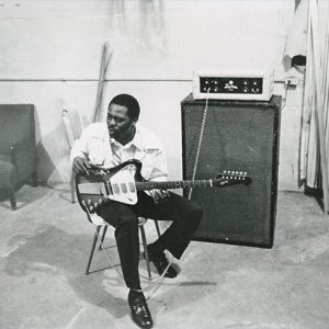 African-American man with electric guitar and amplifiers in studio room