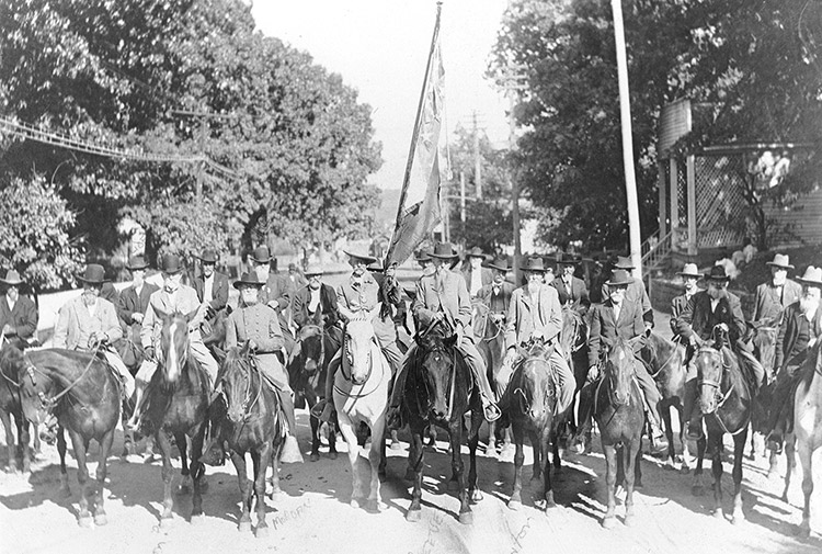 Group of white men in military uniforms on horseback on street