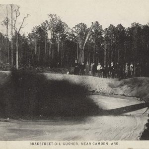 Men observing oil gushing from ground into earthen pool
