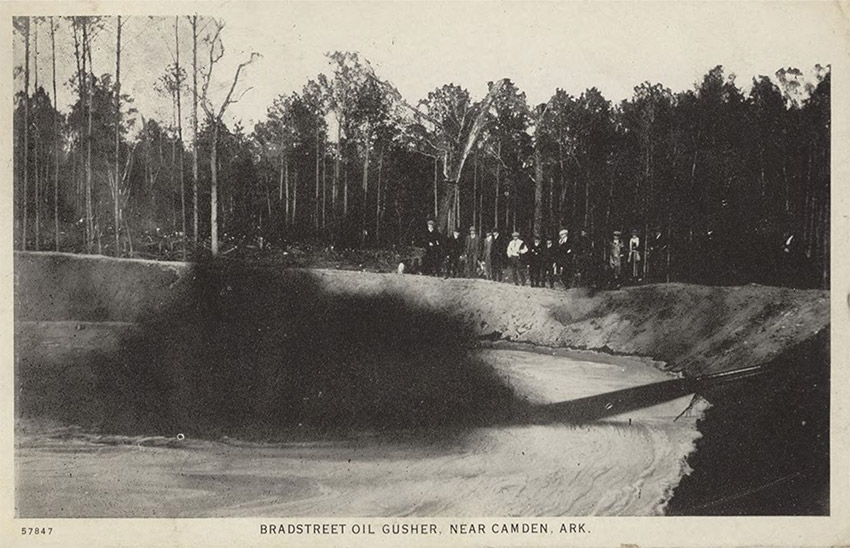 Men observing oil gushing from ground into earthen pool