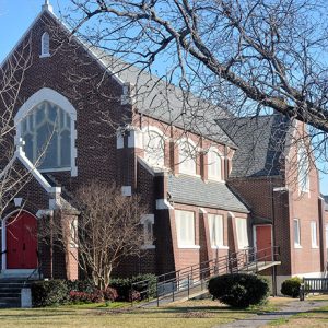 Multistory brick church building with arched windows and entrance way with red doors