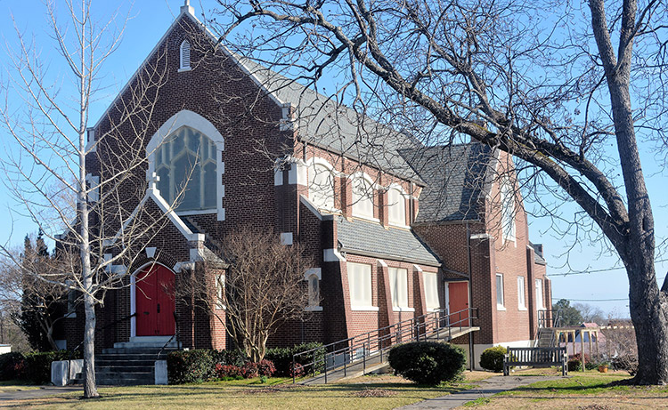 Multistory brick church building with arched windows and entrance way with red doors