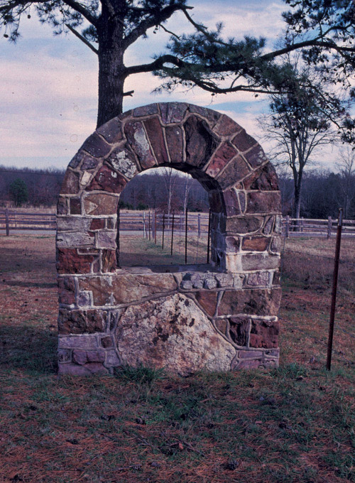 Arched stone block sign frame with fences and trees in the background