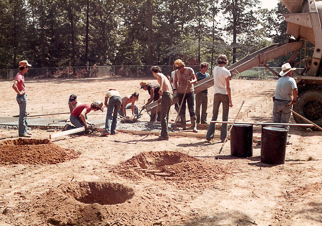 Group of white men with cement truck in a dirt field