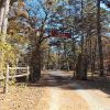 "Camp Tahkodah" entrance on dirt road in forested area