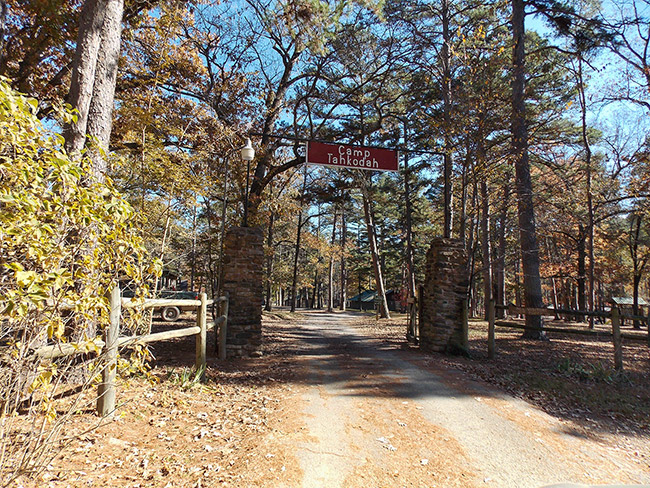 "Camp Tahkodah" entrance on dirt road in forested area